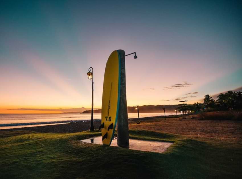 Una tabla de surf colocada en posición vertical durante la puesta de sol.